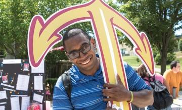 Smiling person, outside, holding a large cut-out anchor