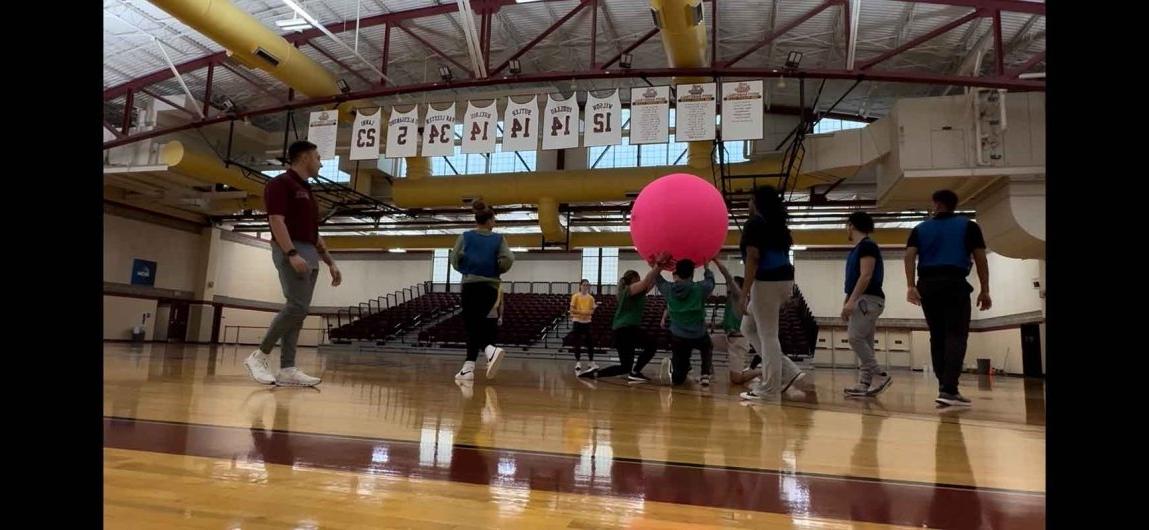 HPE students in gym utilizing engaged learning with giant ball