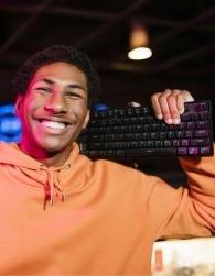 High school student holding computer keyboard on his shoulder and smiling