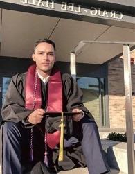 Jonathan sits on steps of Craig-Lee in his cap and gown